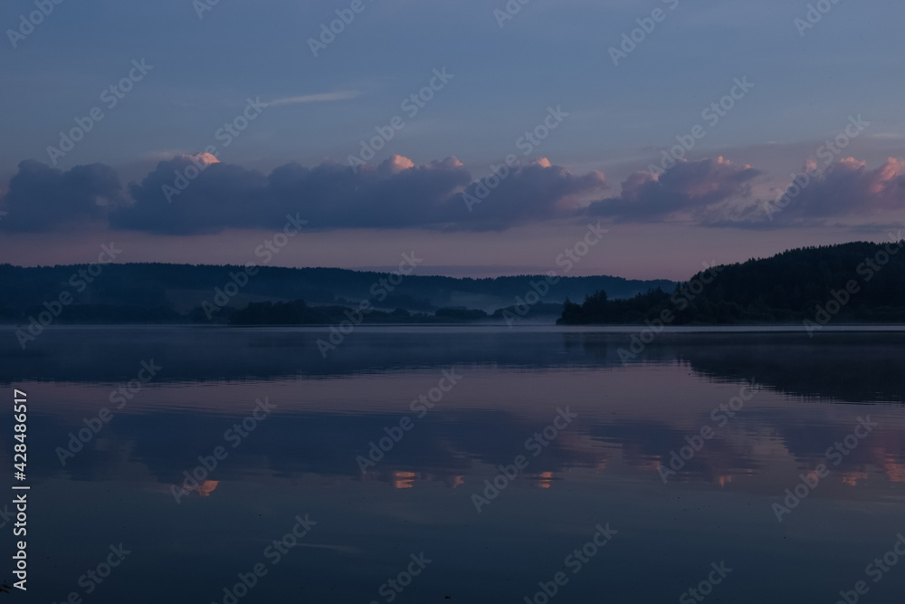 Early morning, just after sunrise, lake view, silhouette of a seated man