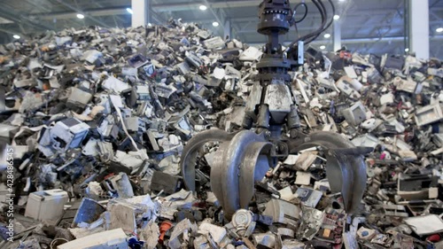Scrap Yard Excavator picks up trash from a heap in a landfill