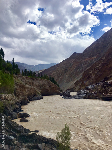 Vertical shot of a muddy river flowing at the foot of bare mountains in Ladakh  India