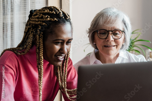 Multi generational women having video call with colleagues using computer app - Multiracial people using laptop computer - Elderly enjoying technology concept - Focus on senior face