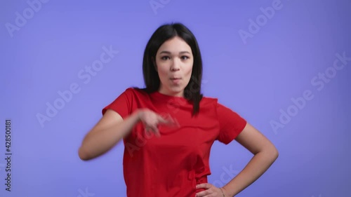 Attractive woman dancing on violet studio background. Girl in red basic wear. Positive mood. Slow motion.
