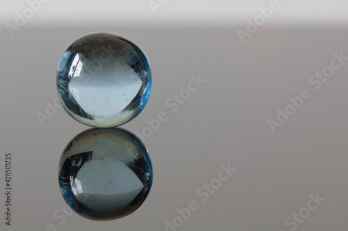 Little clear marble with a mirror surface reflection - stock photo