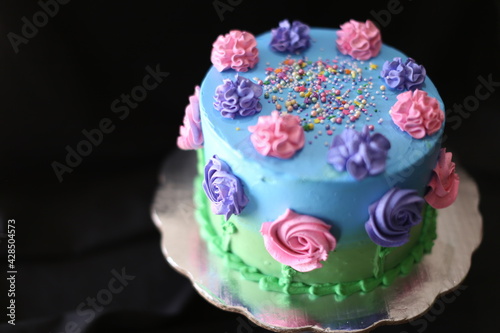 Pastel de cumpleaños decorado con flores de azucar, azul, chispas, verde, pasto