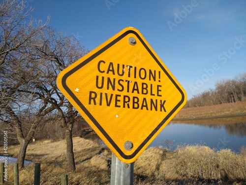 Warning sign "Caution! Unstable riverbank". Black letters on yellow background