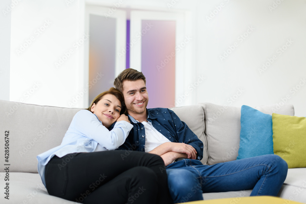 young couple watching tv at home in bright living room
