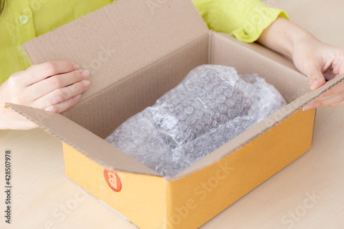 Closeup hand of woman opening parcel box with check product at home, female unpack with knife, delivery and shipping, shipment and express for shop, online shopping store and service concept.