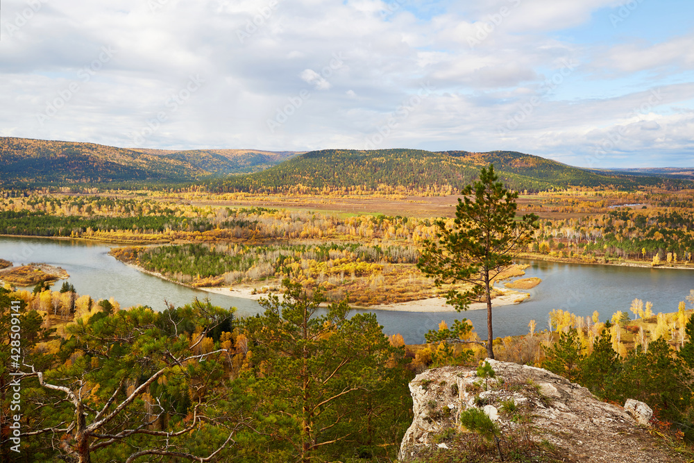 Fototapeta premium Beautiful view from the cliff to the river, forest. Autumn landscape, cloudy sky. 