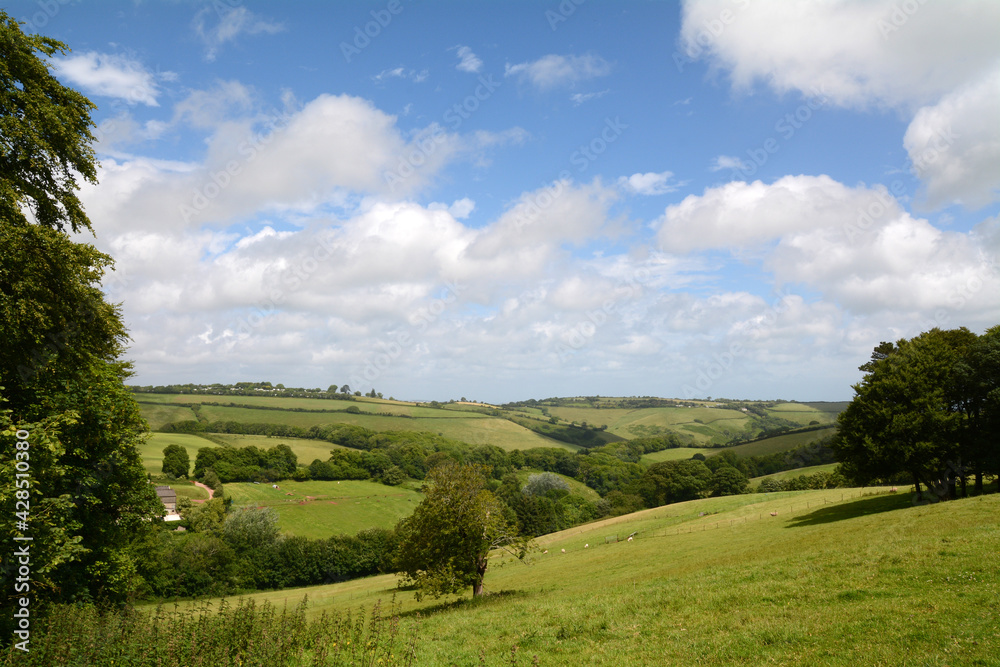 Traditional view of the English countryside with rolling hills, blue sky and white clouds.
