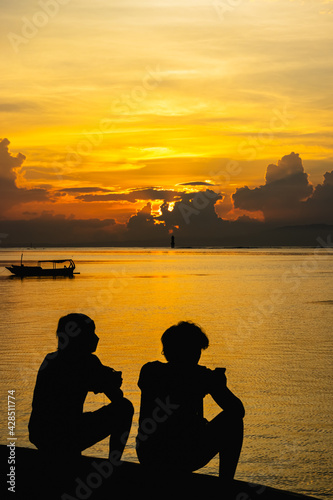 silhouette of a couple sitting on a pier enjoying the sunset