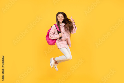 teen girl jump in checkered shirt. happy kid run with backpack. tween child carry school bag.