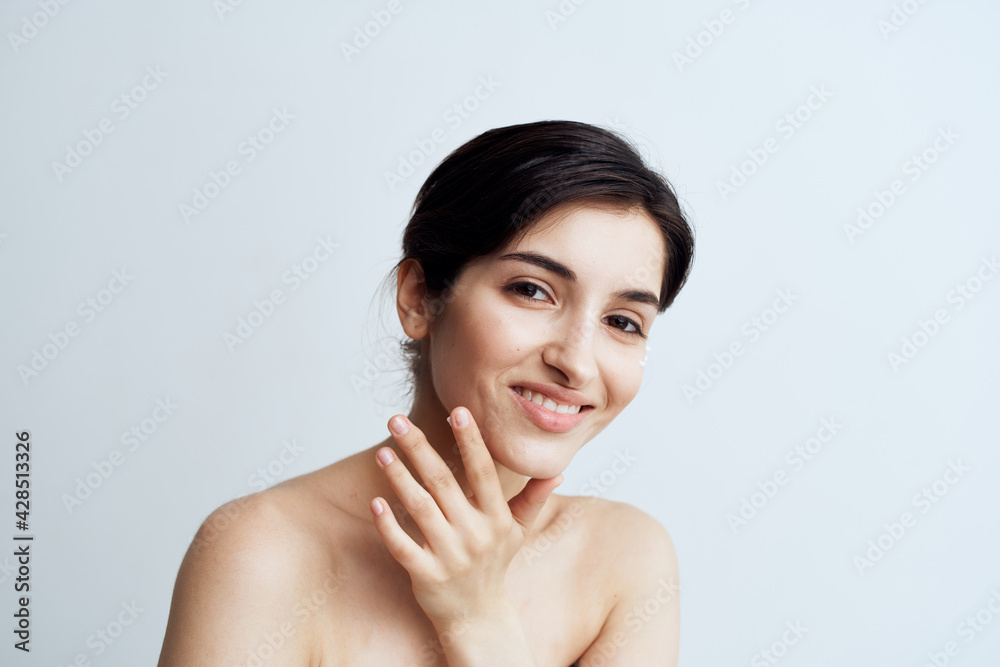 Pretty woman naked shoulders clean skin applies cream to face Pretty woman naked shoulders clean skin applies cream to face