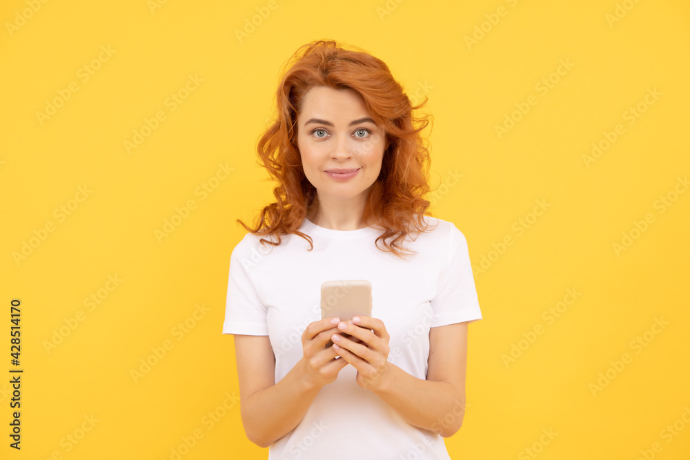 smiling redhead woman chatting in smartphone or make online shopping on yellow background, blogging smiling redhead woman chatting in smartphone or make online shopping on yellow background, blogging