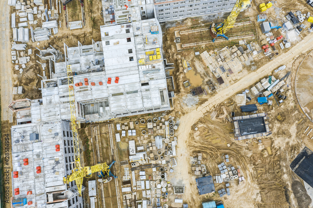busy construction site, shot from above. yellow cranes near the building under construction.