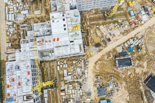 busy construction site, shot from above. yellow cranes near the building under construction.