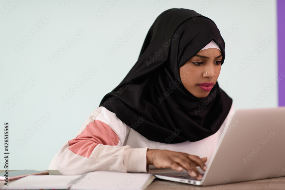 afro girl wearing a hijab is disappointed and sad sitting in her home office and using a laptop afro girl wearing a hijab is disappointed and sad sitting in her home office and using a laptop