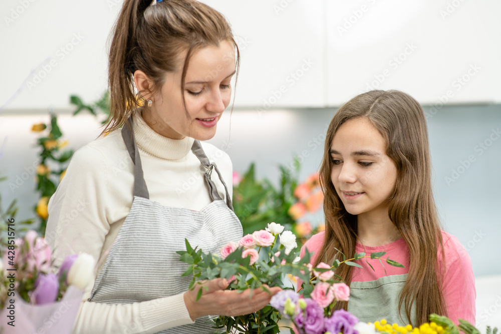 Woman teaches to young girl arranging flower at floral shop Woman teaches to young girl arranging flower at floral shop