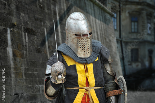 Medieval knight in armor with sword and shield against the background of the castle