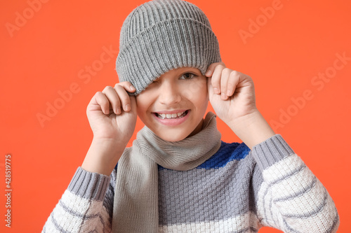 Stylish little boy in warm clothes on color background