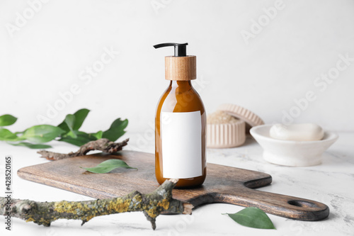 Bottle with natural shampoo on light background