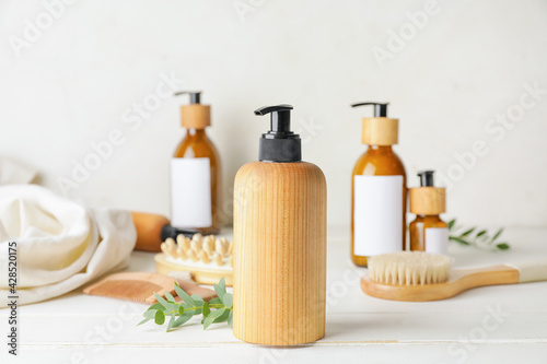 Bottle with natural shampoo on light wooden background