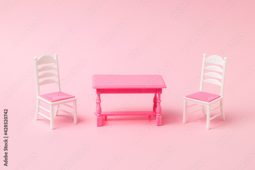 Obraz premium Red table with two chairs on a pink background.