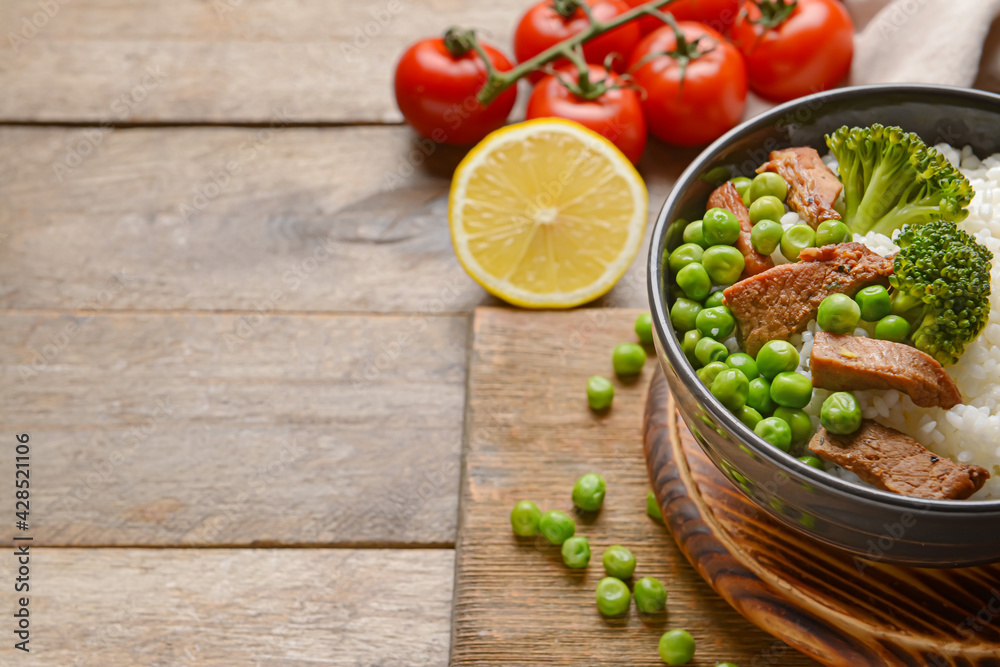 Bowl with tasty rice, meat and vegetables on wooden background Bowl with tasty rice, meat and vegetables on wooden background