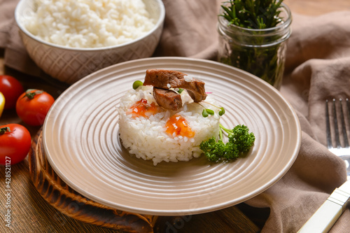 Plate with tasty rice and meat on wooden background, closeup