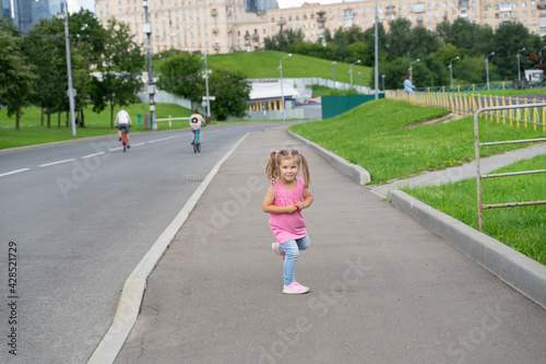 cute little girl with two ponytails enjoys a summer day and a walk
