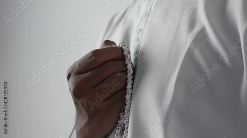 muslim man dhikr using tasbeeh prayer beads or misbaha (with repetitive Arabic text that reads Allah, Muhammad Prophet on the beads) photo