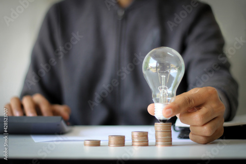 hand holding light bulb on a stack of coins financial ideas and financial growth. business and creative concept.