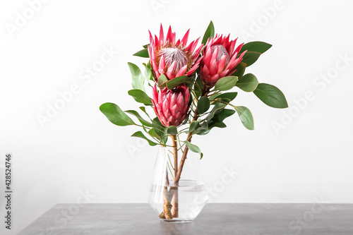 Vase with beautiful protea flowers on light background photo