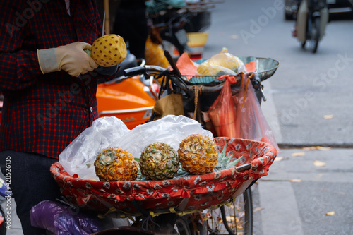 Female peeling a small pineapple in a typical Asian outdoor market