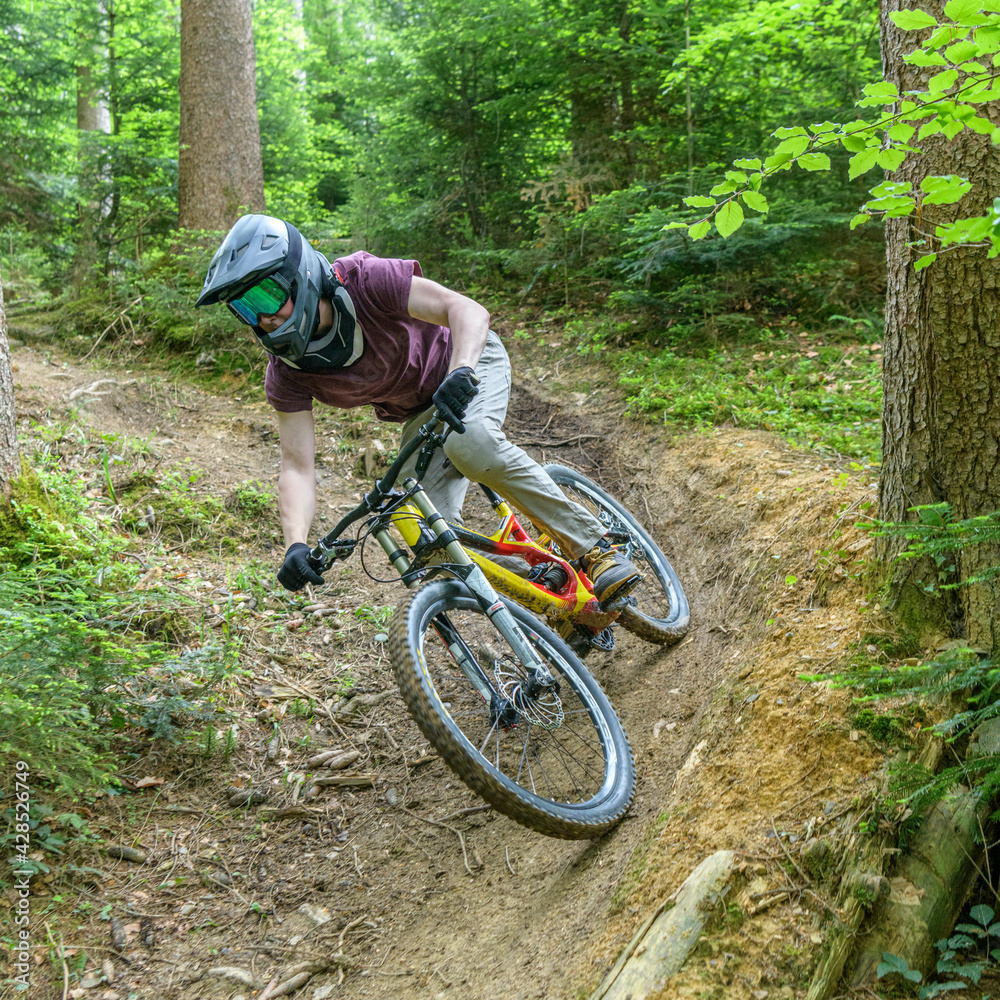 Fototapeta premium Mutiger Downhiller auf einem Wald-Trail 