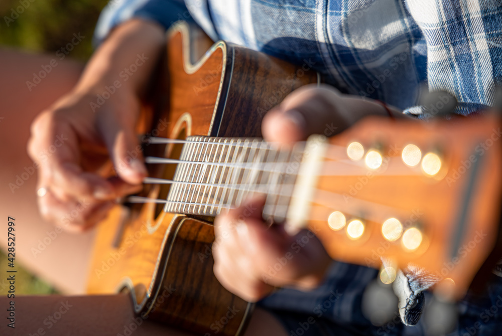 Fototapeta premium Woman at sunset playing the ukulele