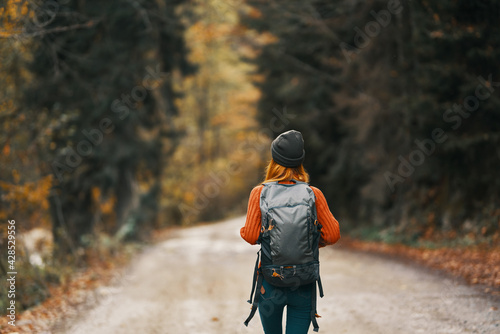 Traveler with a backpack in the forest on the road in autumn trees model photo
