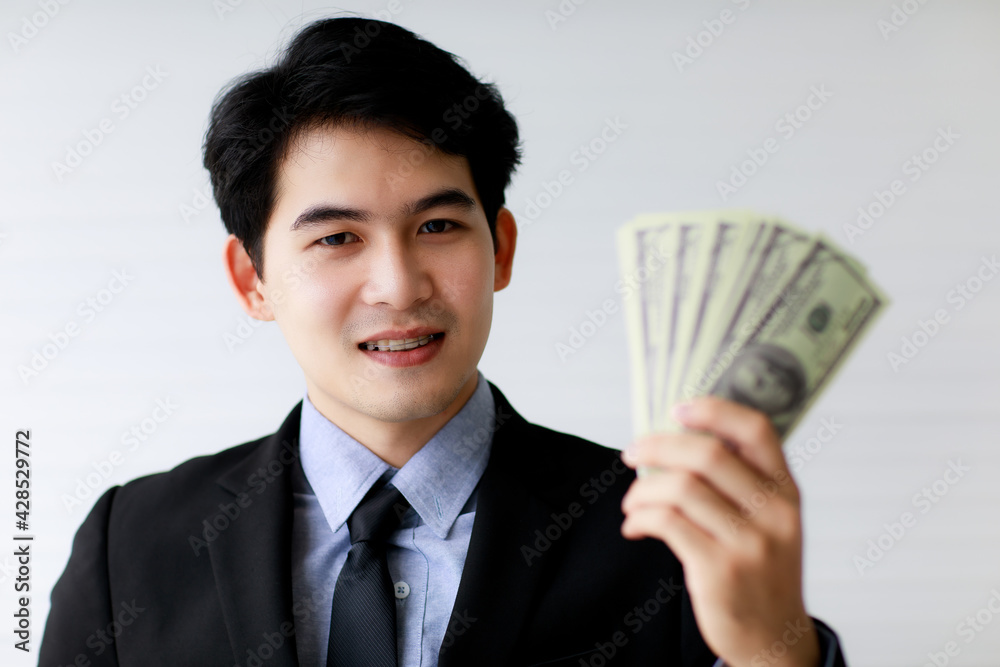 Selective focus on Asuab businessman holding dollar bank notes or money with blur foreground. Financial Concept. Selective focus on Asuab businessman holding dollar bank notes or money with blur foreground. Financial Concept.