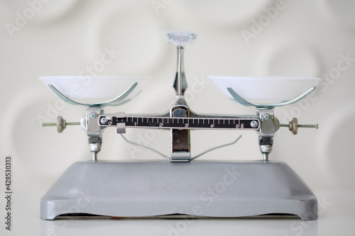 A weight and balance scale with two white plates, was put on the table in laboratory for educational or medical purpose.