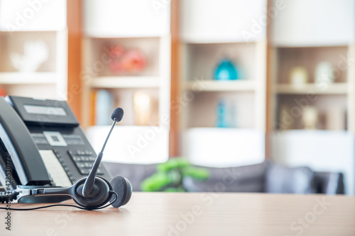Close up soft focus on headset with telephone devices at office desk for customer service support.VOIP headset for customer service support (call center) concept.