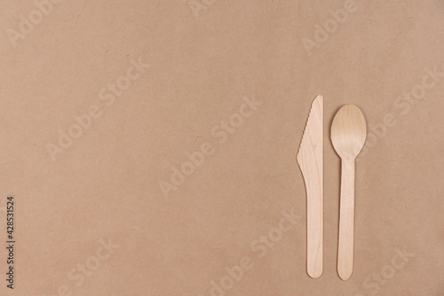 Disposable wooden spoon and knife lie on craft paper