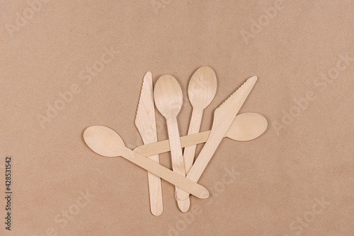 Several disposable spoons and knives lie on craft paper