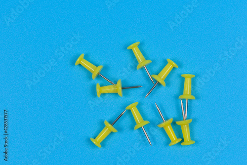 Several yellow stationery pins on blue background