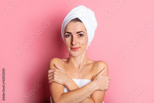 spa treatments, smiling young woman with a towel on her head on a pink background