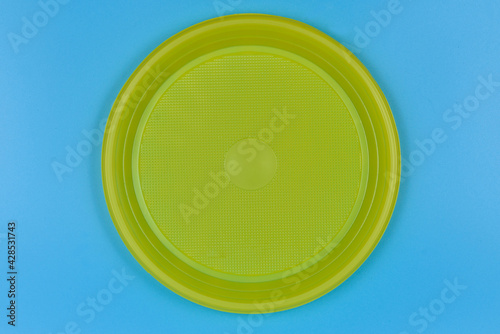 Disposable yellow plastic plate on blue background