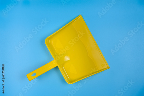 Yellow garbage scoop on blue background. View from above