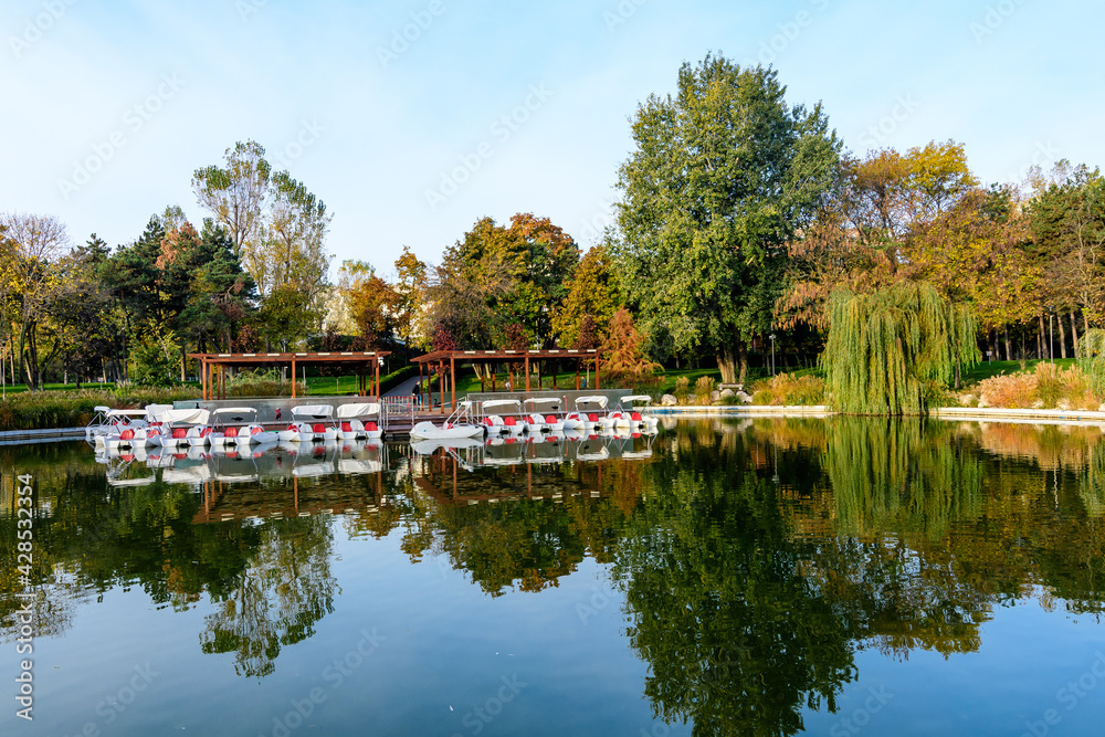 Landscape with the lake and green and yellow trees in Drumul Taberei Park, also known as Moghioros Park, in Bucharest, Romania, at sunrise in an autumn morning.