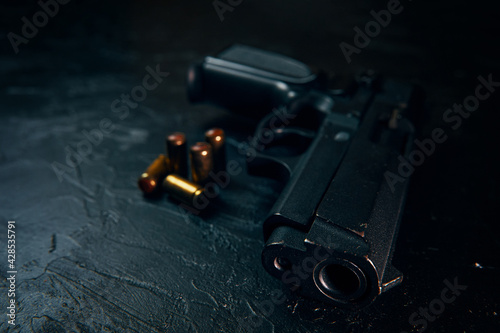 Black gun and bullets on concrete table. Firearms on dark background. Weapons and ammunition. Concept of crime and physical evidence. Pistol for defense or attack.