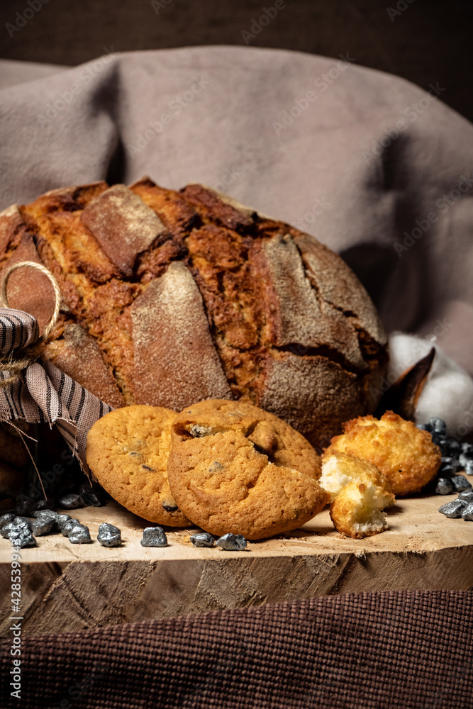 Fototapeta premium Pieces of broken biscuits lie on a wooden stump next to bread