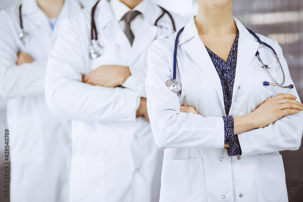 Doctors standing as a team with arms crossed in clinic. Medical help, insurance and medicine concept Doctors standing as a team with arms crossed in clinic. Medical help, insurance and medicine concept