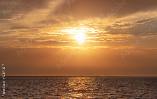 Colorful red sunset and bright sun on the horizon of the ocean beach.