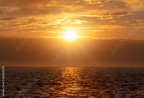 Colorful red sunset and bright sun on the horizon of the ocean beach.